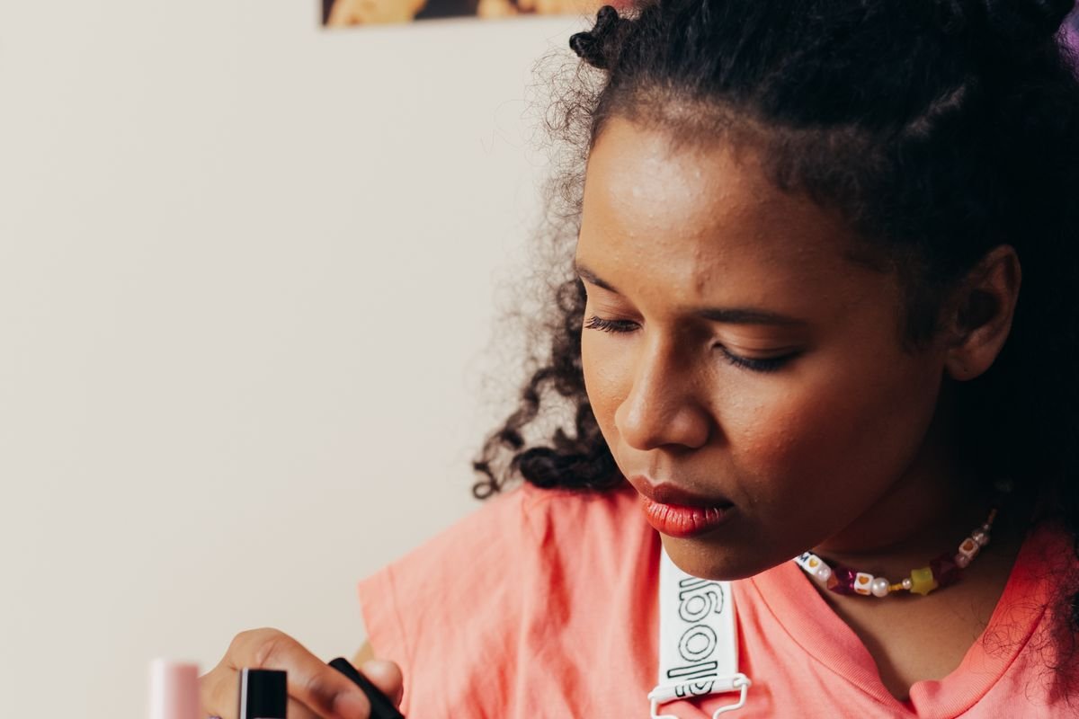 Black woman applying nail polish during a manicure