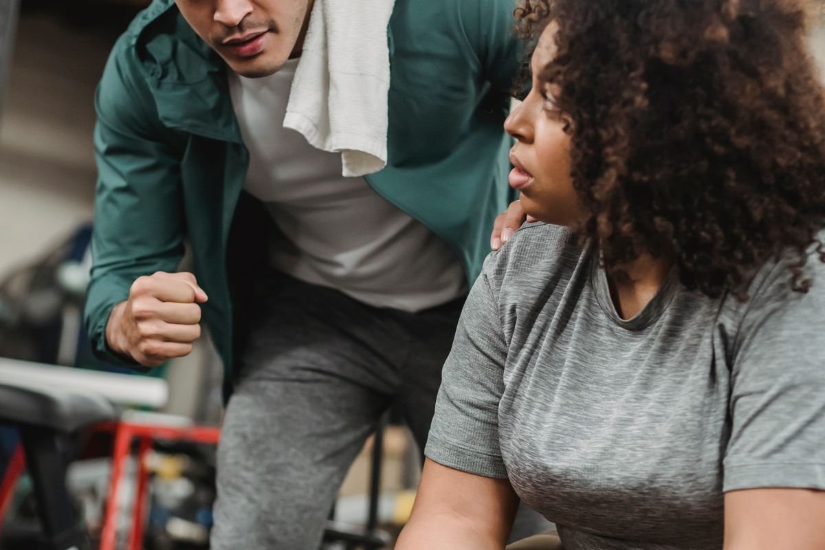Black trainer supporting a Black client during a guided recovery exercise